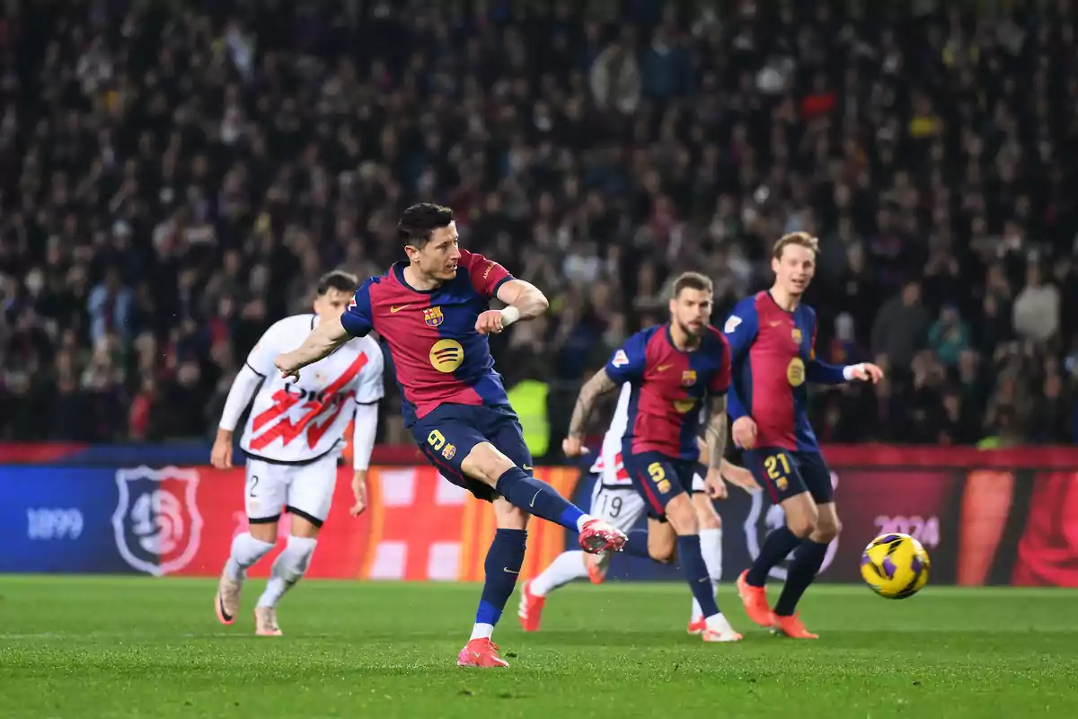 Un jugador de fútbol del Barcelona patea el balón durante un partido mientras otros jugadores observan en el campo.