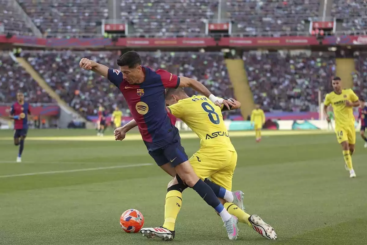 Dos jugadores de fútbol compiten por el balón en un estadio lleno de espectadores. Dos jugadores de fútbol compiten por el balón en un estadio lleno de espectadores.
