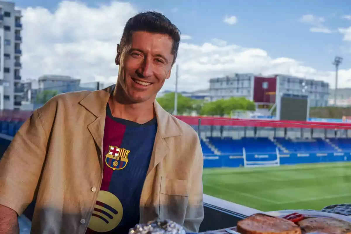 Robert Lewandowski con una camiseta del FC Barcelona y una chaqueta beige, posando frente al estadio Johan Cruyff.