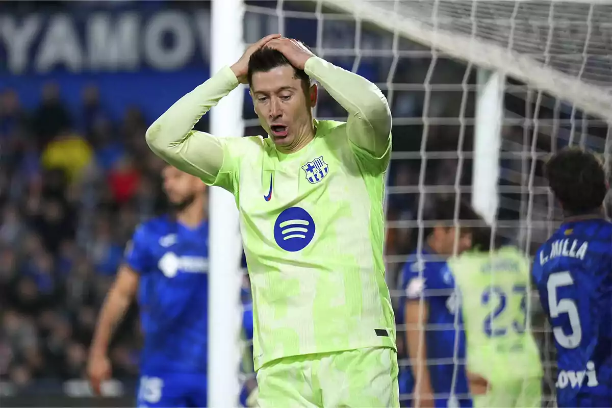 A soccer player in a light green uniform puts his hands to his head in frustration during a match.