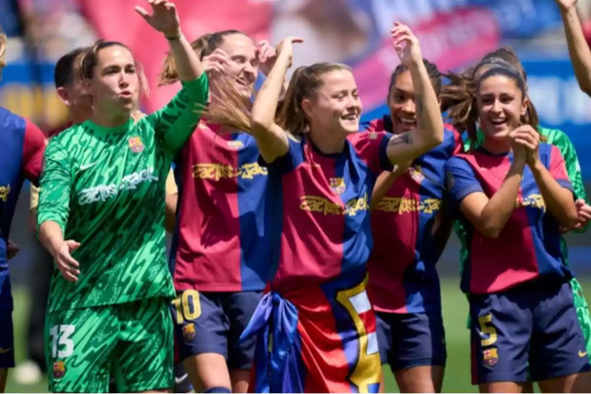 Un grupo de jugadoras de fútbol celebra en el campo, vistiendo uniformes del FC Barcelona, con sonrisas y gestos de alegría. Un grupo de jugadoras de fútbol celebra en el campo, vistiendo uniformes del FC Barcelona, con sonrisas y gestos de alegría.