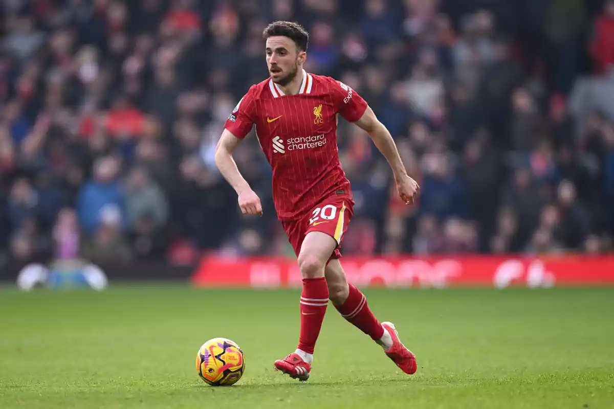 Soccer player in a red uniform controlling the ball on a field during a match.