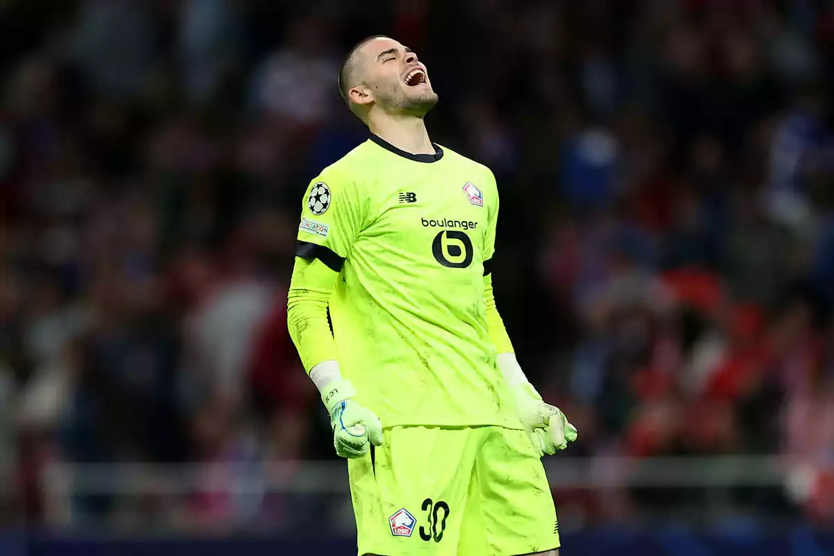 Un portero de fútbol con uniforme verde brillante expresa emoción en el campo durante un partido.