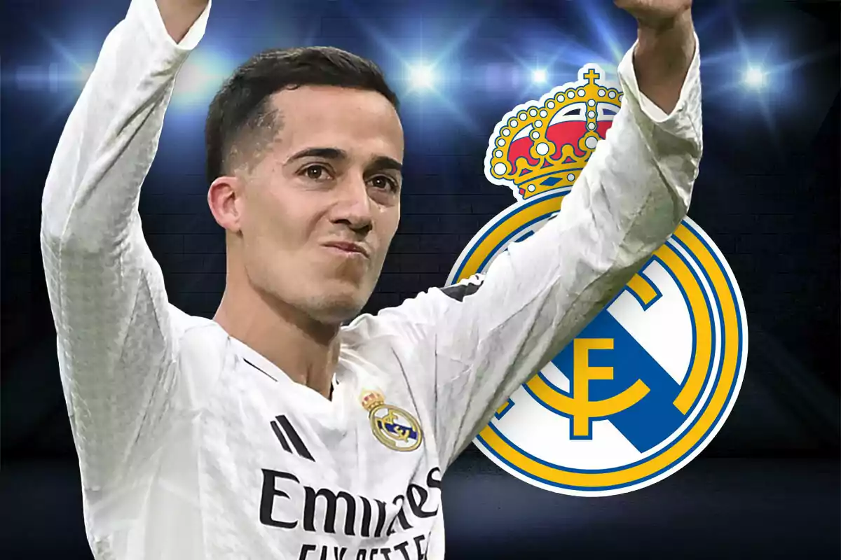Soccer player in a white uniform raising his arms in front of the Real Madrid crest.