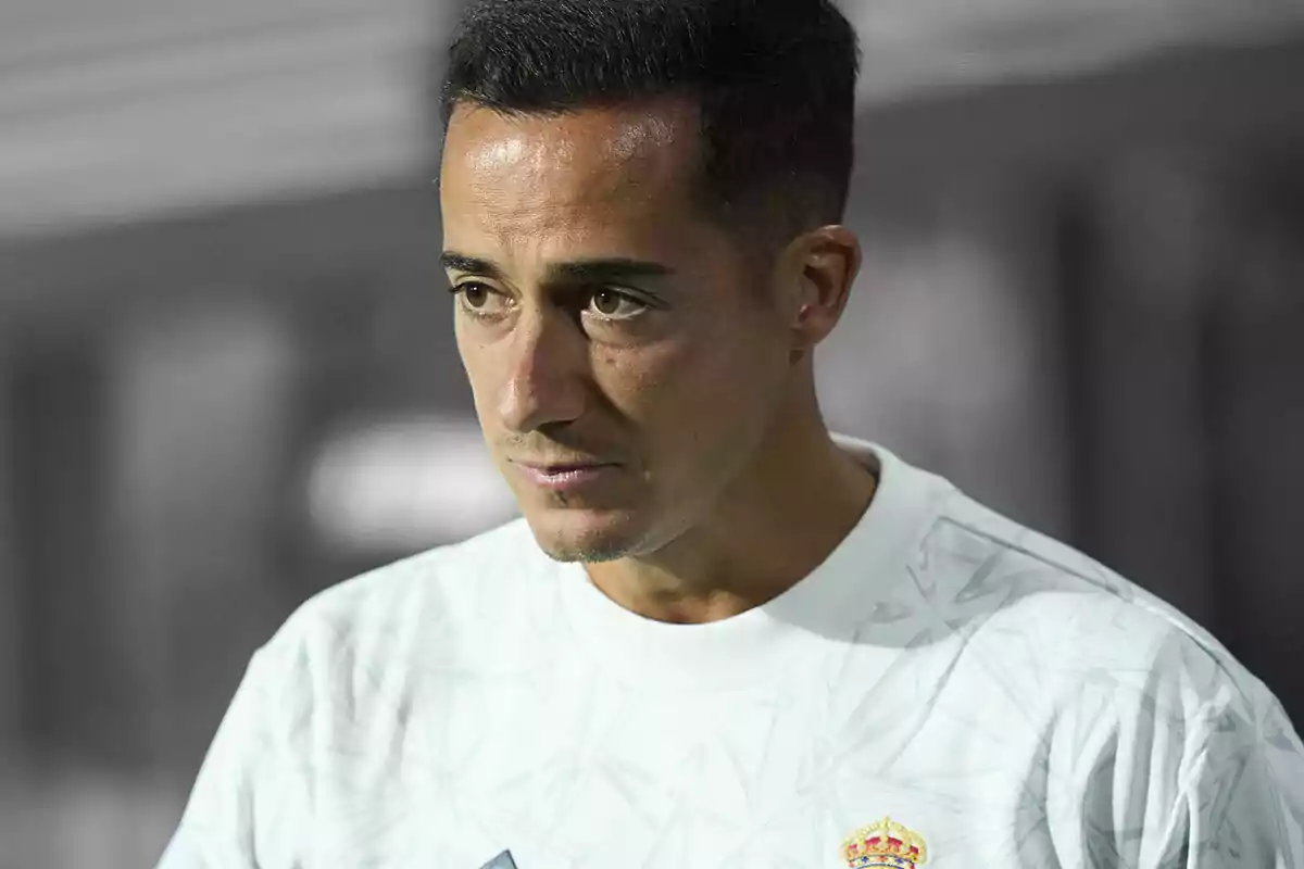 Lucas Vázquez con una camiseta blanca del Real Madrid, mirando hacia la derecha con una expresión seria.