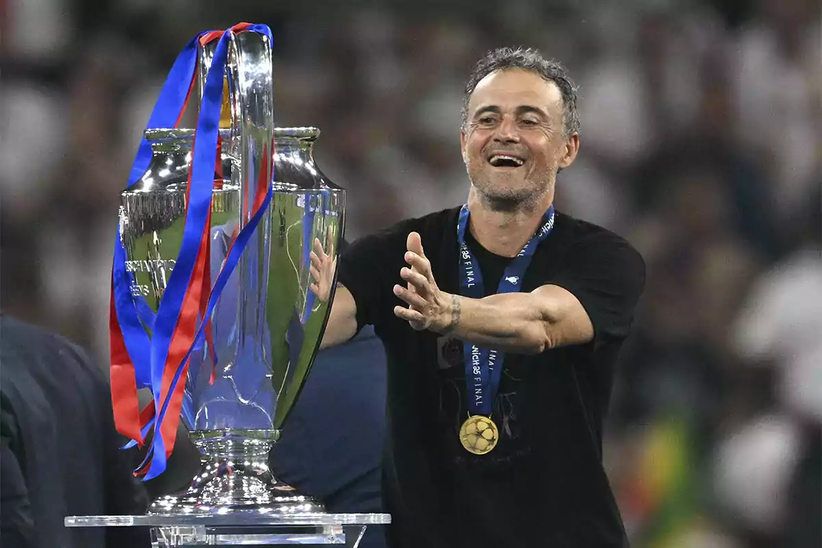 Smiling man with a medal celebrating next to a large soccer trophy decorated with red and blue ribbons Smiling man with a medal celebrating next to a large soccer trophy decorated with red and blue ribbons
