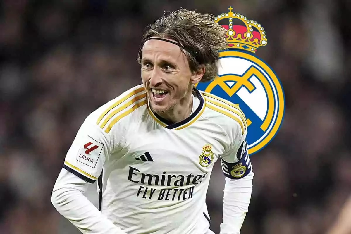 Luka Modric con el uniforme del Real Madrid sonríe mientras corre en el campo, con el escudo del equipo en el fondo.