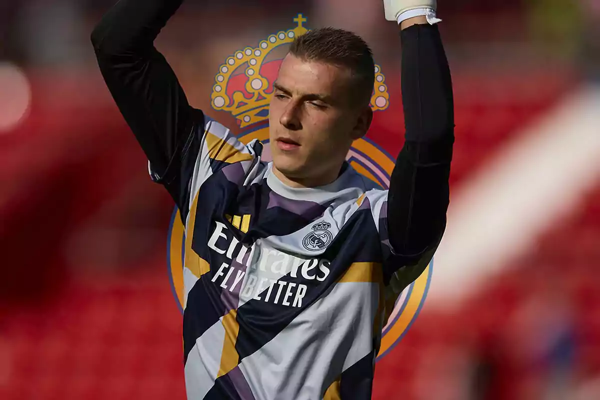 Andriy Lunin con uniforme de entrenamiento del Real Madrid levantando los brazos.