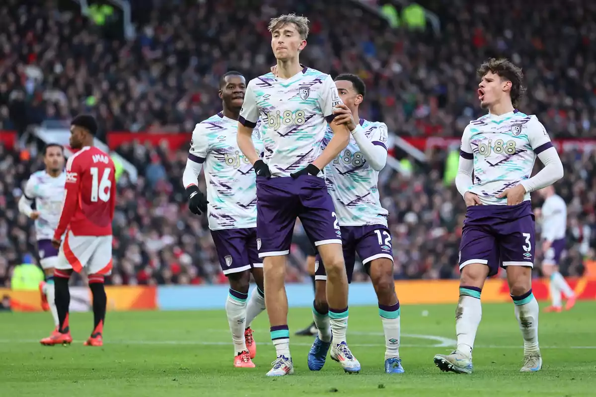 Football players celebrating on the field during a match with the crowd in the background.