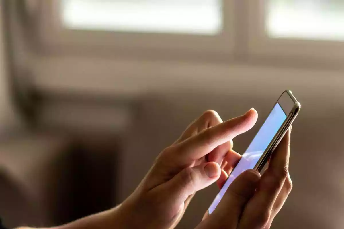 Manos de una mujer utilizando un teléfono móvil táctil, con el fondo de la imagen difuminado Manos de una mujer utilizando un teléfono móvil táctil, con el fondo de la imagen difuminado
