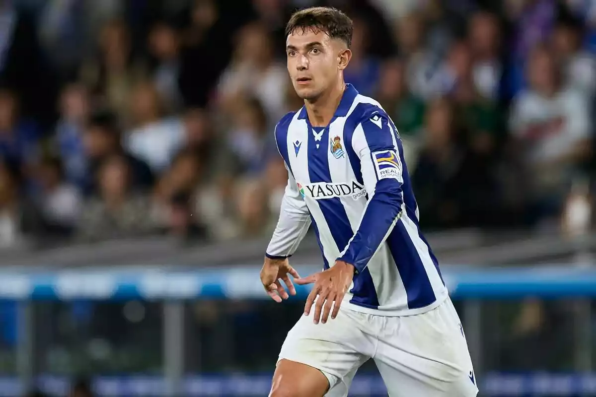 Un jugador de fútbol con uniforme azul y blanco en el campo durante un partido.