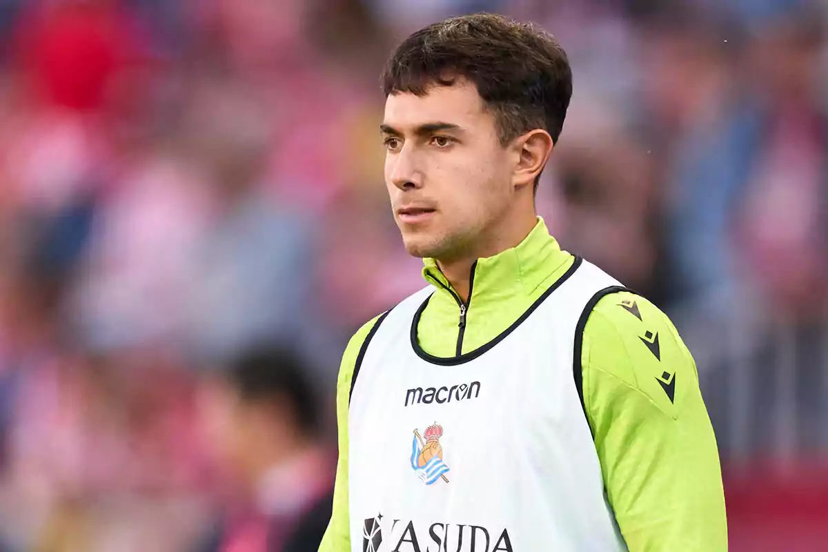 Martín Zubimendi con uniforme de entrenamiento verde y chaleco blanco en un estadio. Martín Zubimendi con uniforme de entrenamiento verde y chaleco blanco en un estadio.