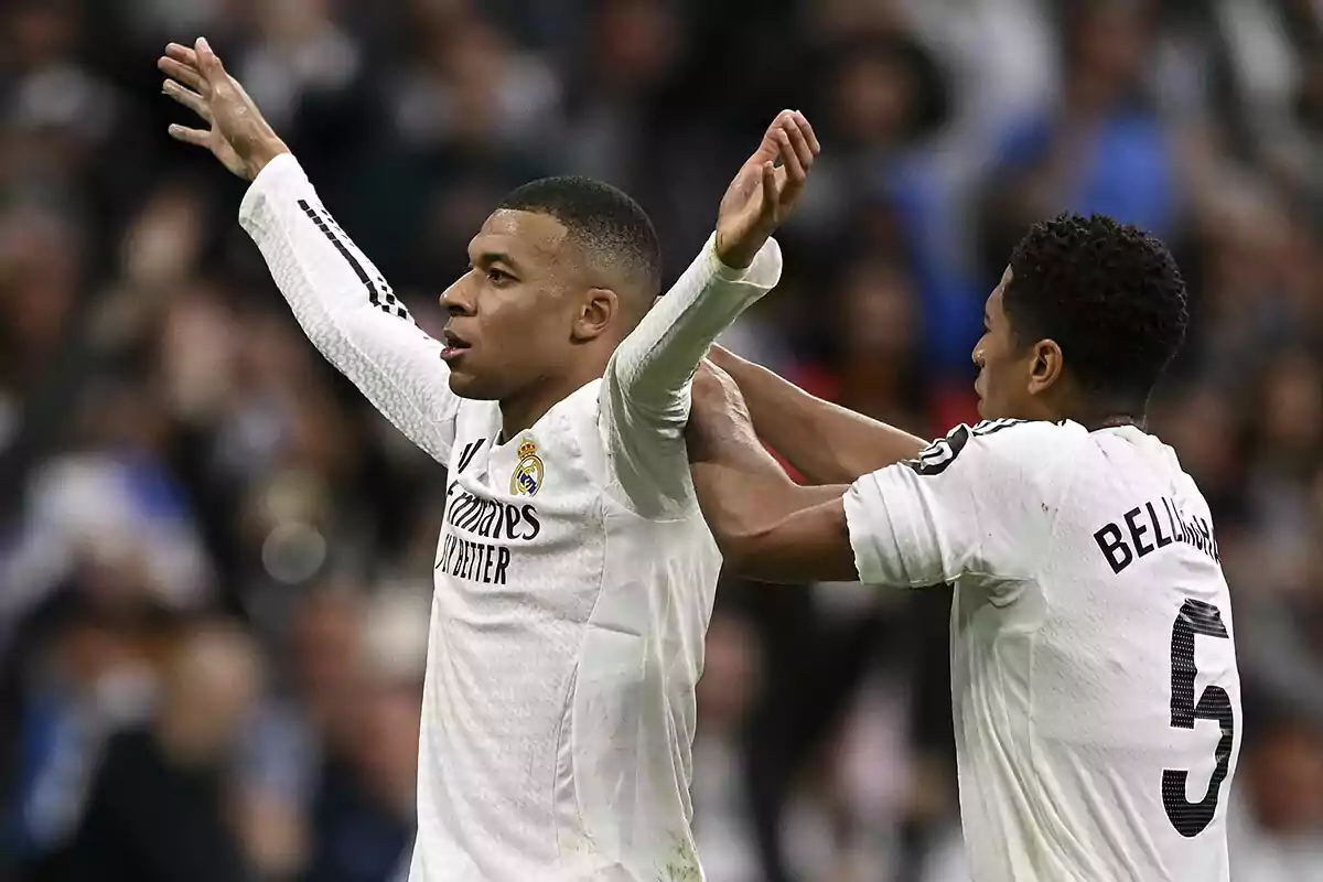 Dos jugadores de fútbol con uniforme blanco celebran en el campo. Dos jugadores de fútbol con uniforme blanco celebran en el campo.