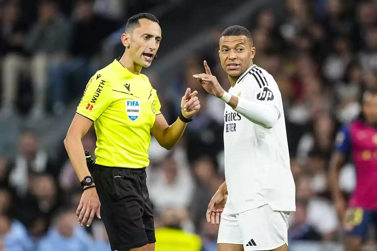 Un árbitro de fútbol hablando con un jugador en el campo durante un partido.