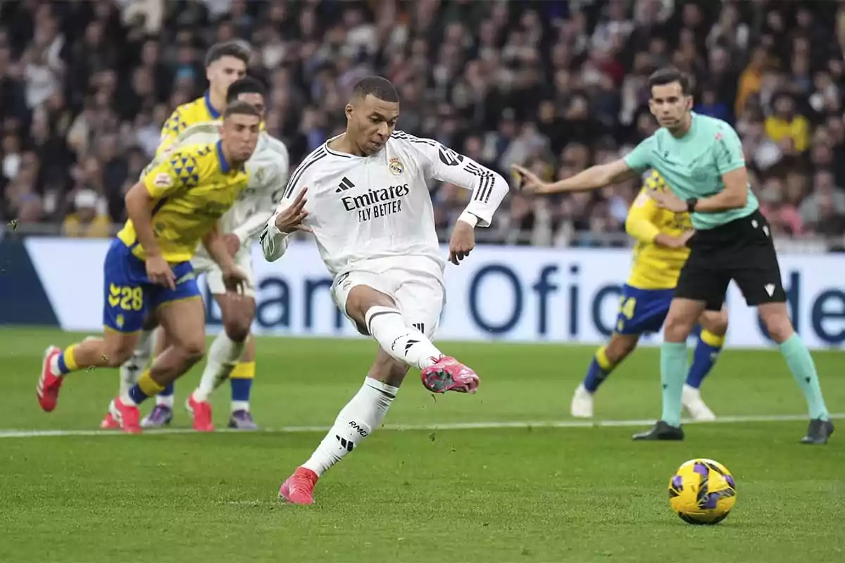 A Real Madrid soccer player takes a penalty kick during a match, while other players and the referee watch. A Real Madrid soccer player takes a penalty kick during a match, while other players and the referee watch.
