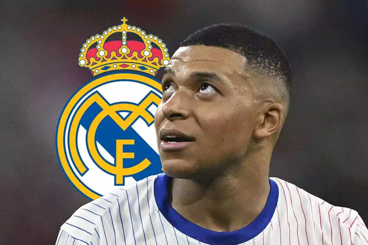 Kylian Mbappé con una camiseta a rayas mira hacia arriba con el logo del Real Madrid en el fondo.