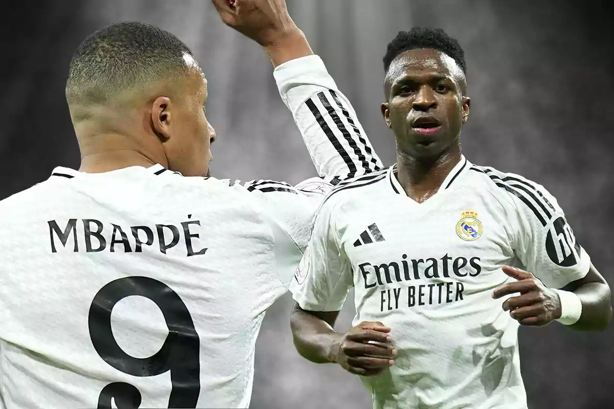 Dos futbolistas con uniformes blancos en un campo de fútbol, uno de espaldas y otro de frente.