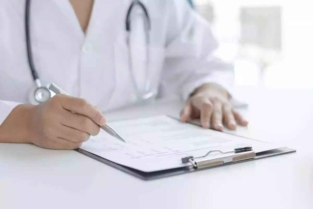 Médico en una consulta rellenando un informe Médico en una consulta rellenando un informe