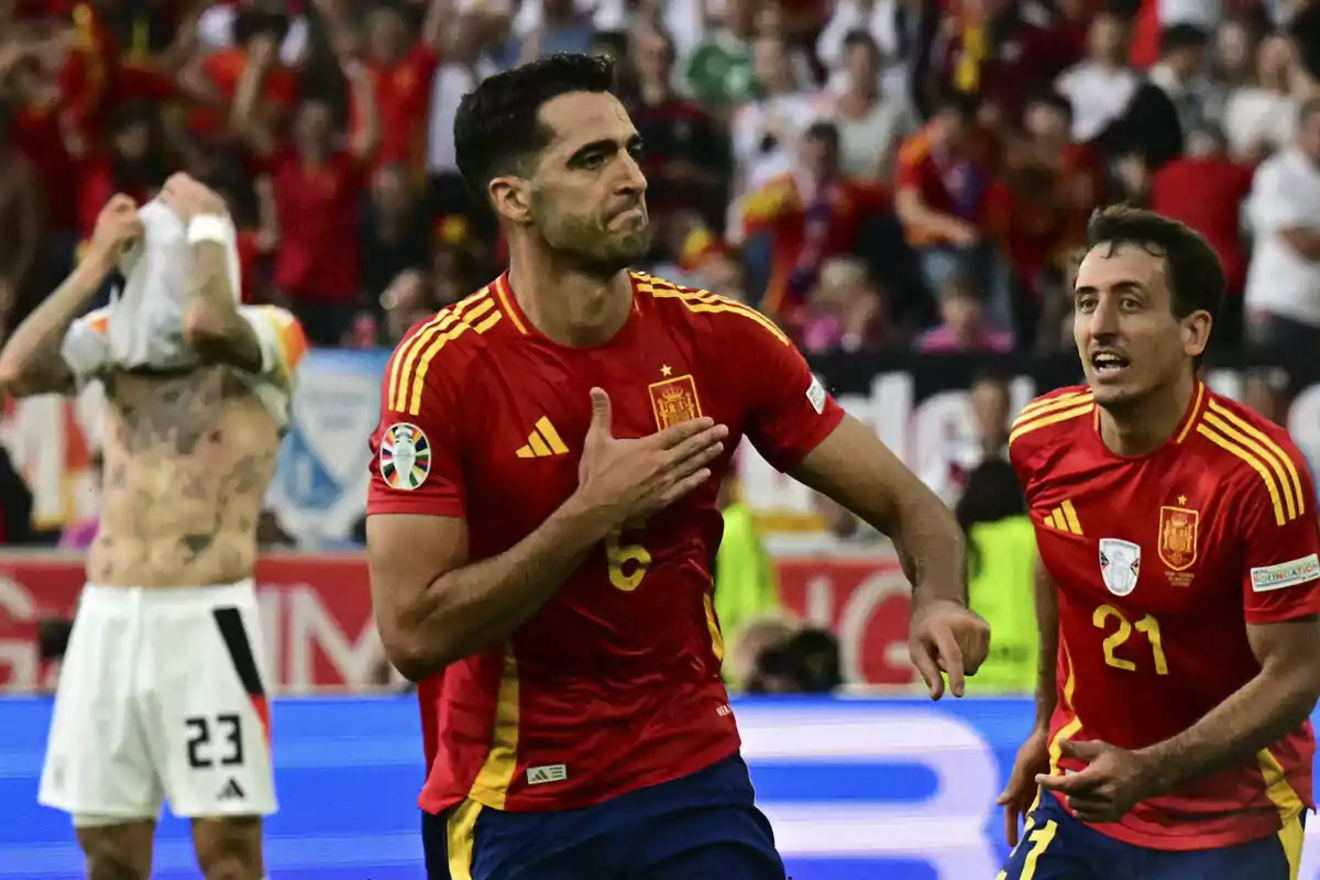 Mikel Merino celebra un gol durante un partido mientras un jugador del equipo contrario muestra frustración.