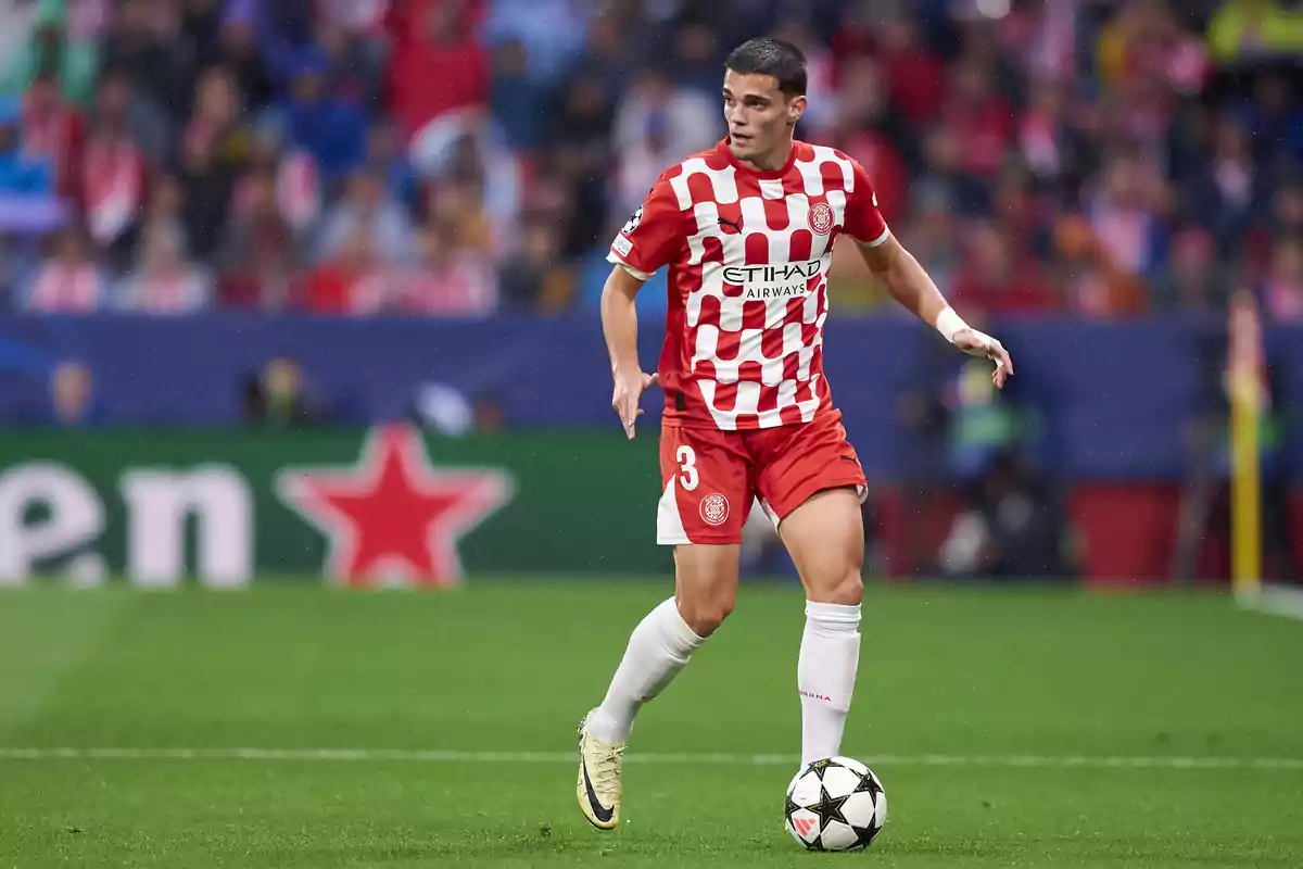 A player in a red and white uniform controls the ball on the field during a match.