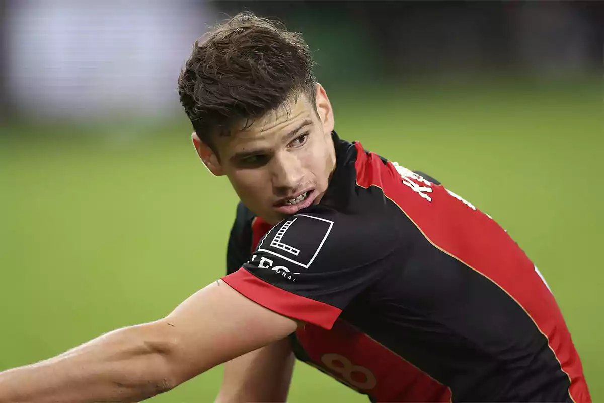 Milos Kerkez con uniforme negro y rojo en el campo de juego. Milos Kerkez con uniforme negro y rojo en el campo de juego.