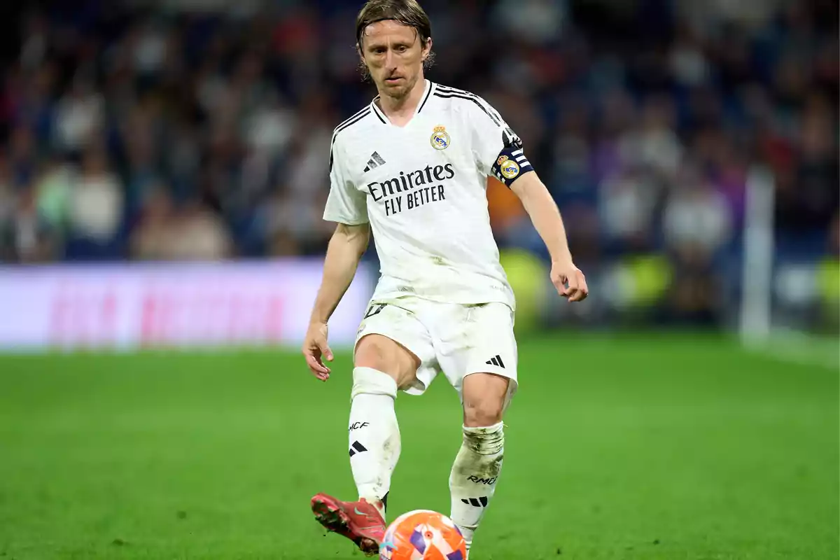A player in a white uniform controls the ball on the field during a match. A player in a white uniform controls the ball on the field during a match.