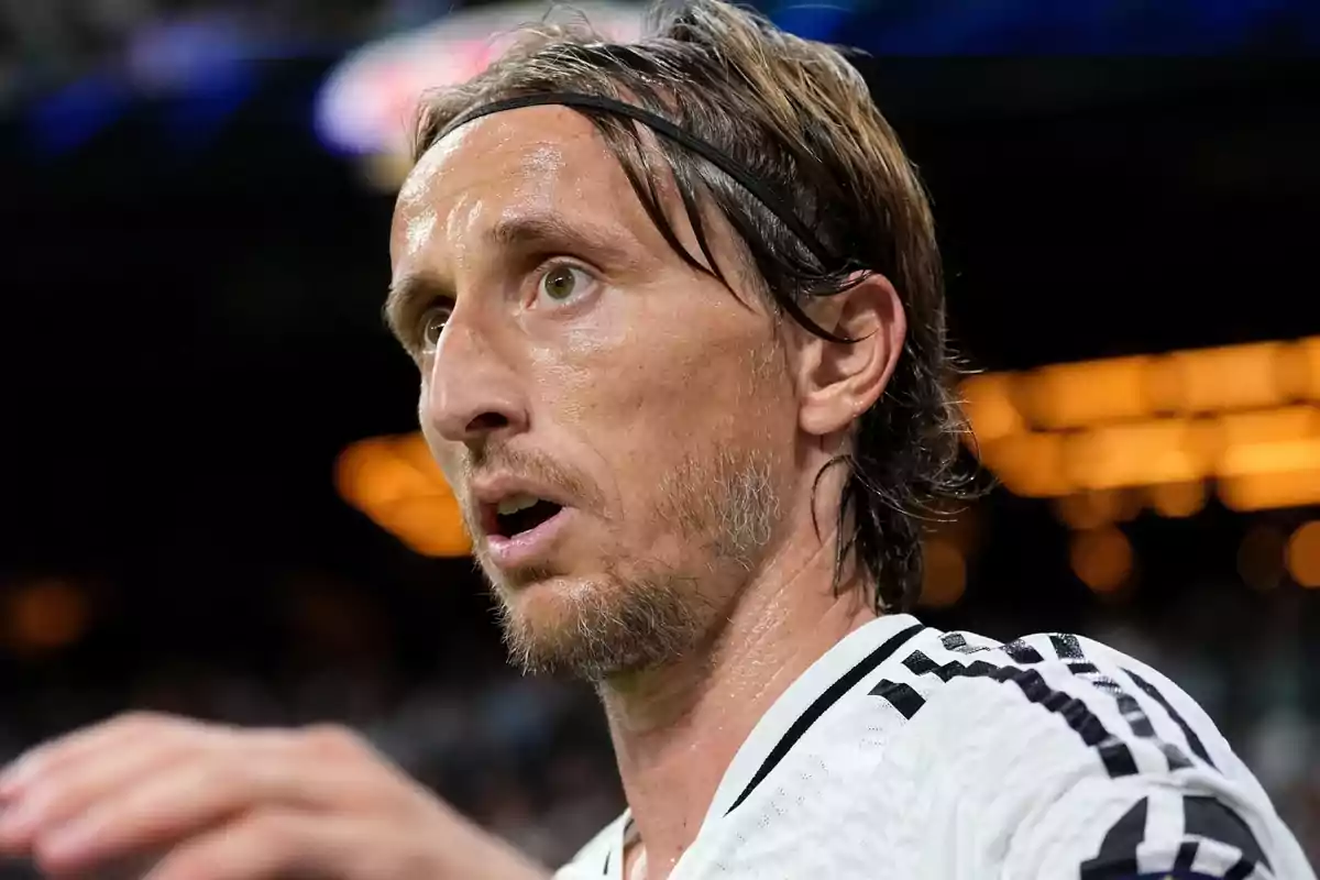 A soccer player in a black and white jersey, with a concentrated expression on his face.