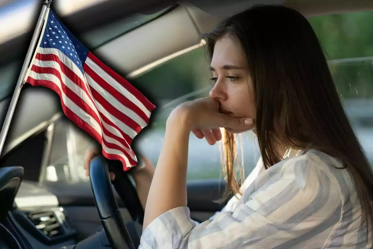 Mujer pensativa sentada al volante de un auto con una bandera de Estados Unidos al frente. Mujer pensativa sentada al volante de un auto con una bandera de Estados Unidos al frente.