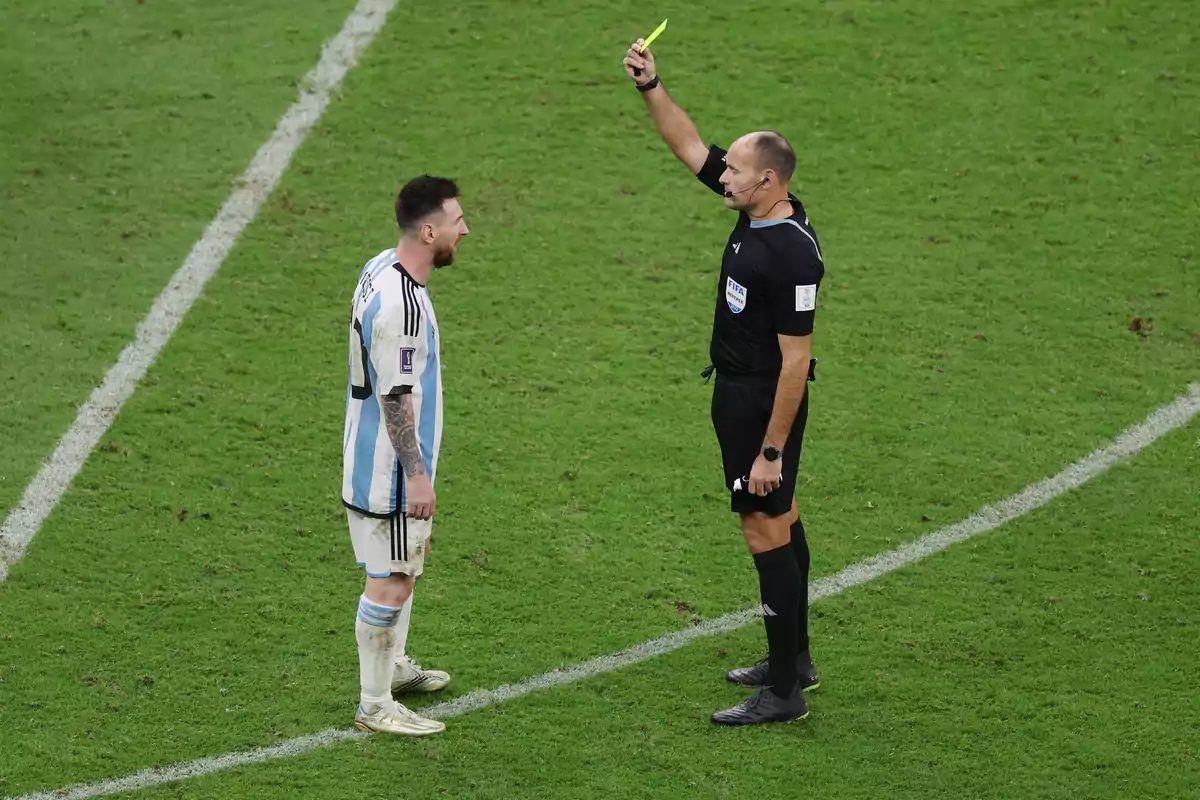 A referee shows a yellow card to a player on the field.