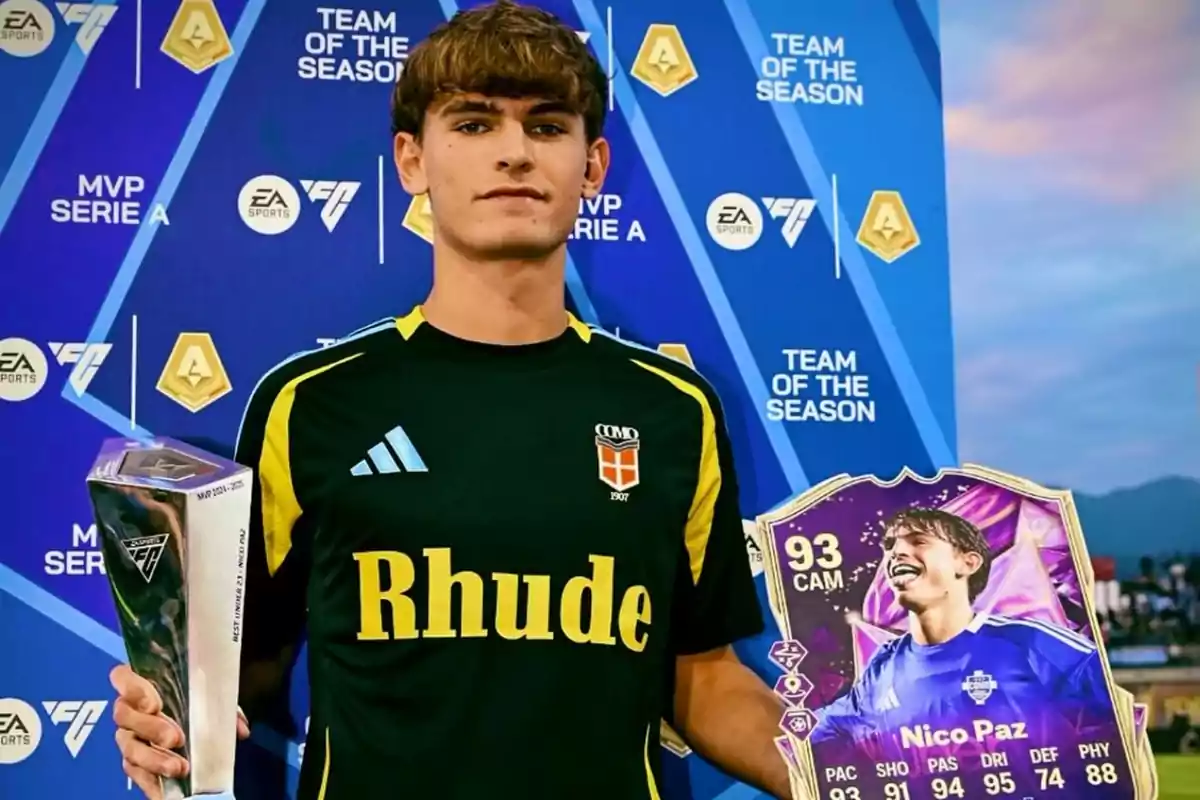 Joven futbolista con camiseta negra sostiene un trofeo plateado y una carta de videojuego con su imagen en un evento de premiación de EA Sports Joven futbolista con camiseta negra sostiene un trofeo plateado y una carta de videojuego con su imagen en un evento de premiación de EA Sports