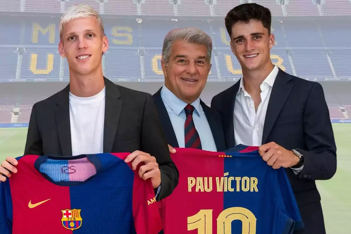 Three people pose in a soccer stadium, two of them holding FC Barcelona jerseys.