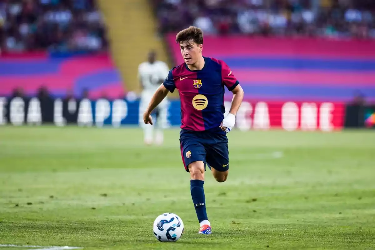 Un jugador de fútbol del FC Barcelona corriendo con el balón en un campo de fútbol durante un partido.