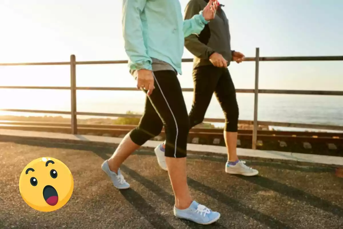 Dos personas caminando al aire libre junto a una barandilla con un emoji sorprendido en la esquina inferior izquierda.