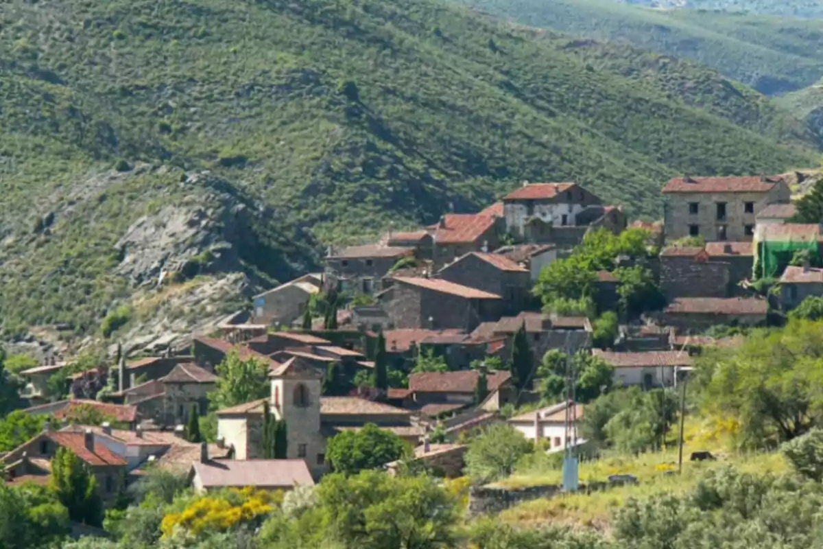 Vista panorámica de un pequeño pueblo con casas de tejados rojos rodeado de colinas verdes. Vista panorámica de un pequeño pueblo con casas de tejados rojos rodeado de colinas verdes.