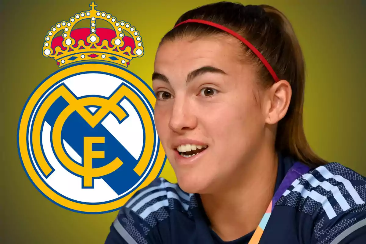 Una persona con una cinta roja en el cabello sonríe frente al escudo del Real Madrid sobre un fondo amarillo.