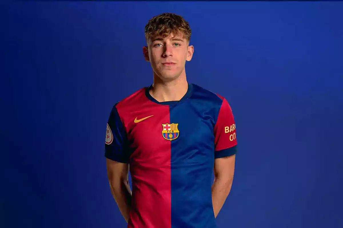 Un jugador de fútbol con el uniforme del FC Barcelona posando frente a un fondo azul.