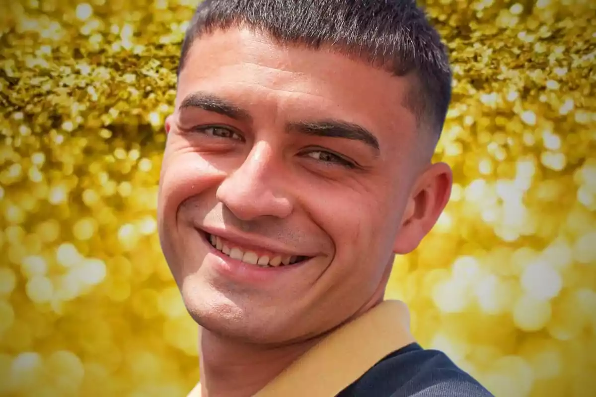 Un hombre sonriente con cabello corto y oscuro, con un fondo brillante y dorado.