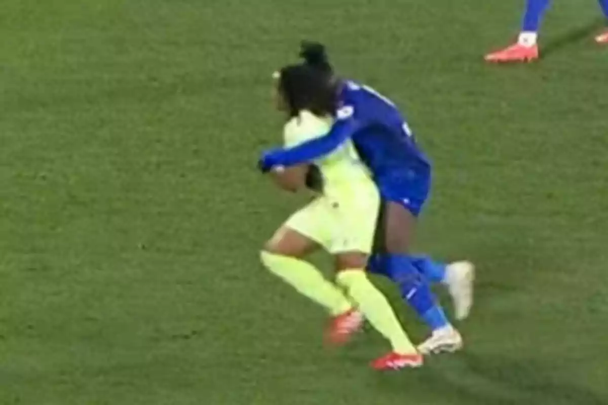 Two soccer players on the field, one in a blue uniform hugging another in a yellow uniform. Two soccer players on the field, one in a blue uniform hugging another in a yellow uniform.