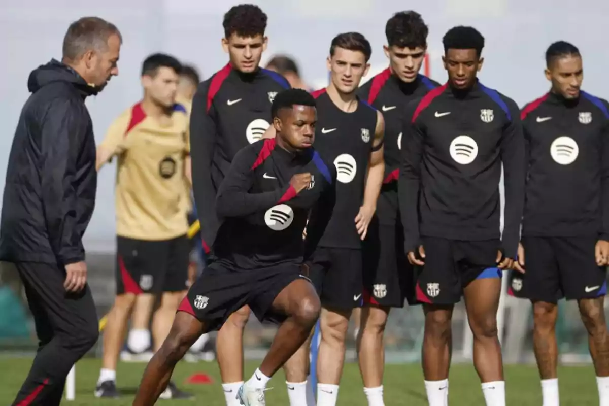 A group of FC Barcelona players training on the field, with one of them running at the front while the others watch.