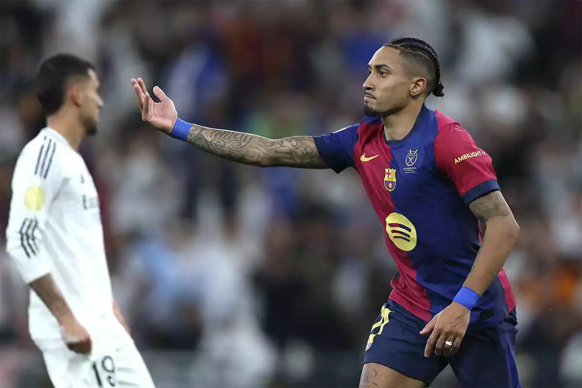 A Barcelona soccer player gestures with his hand during a match while a player from the opposing team is out of focus in the background.