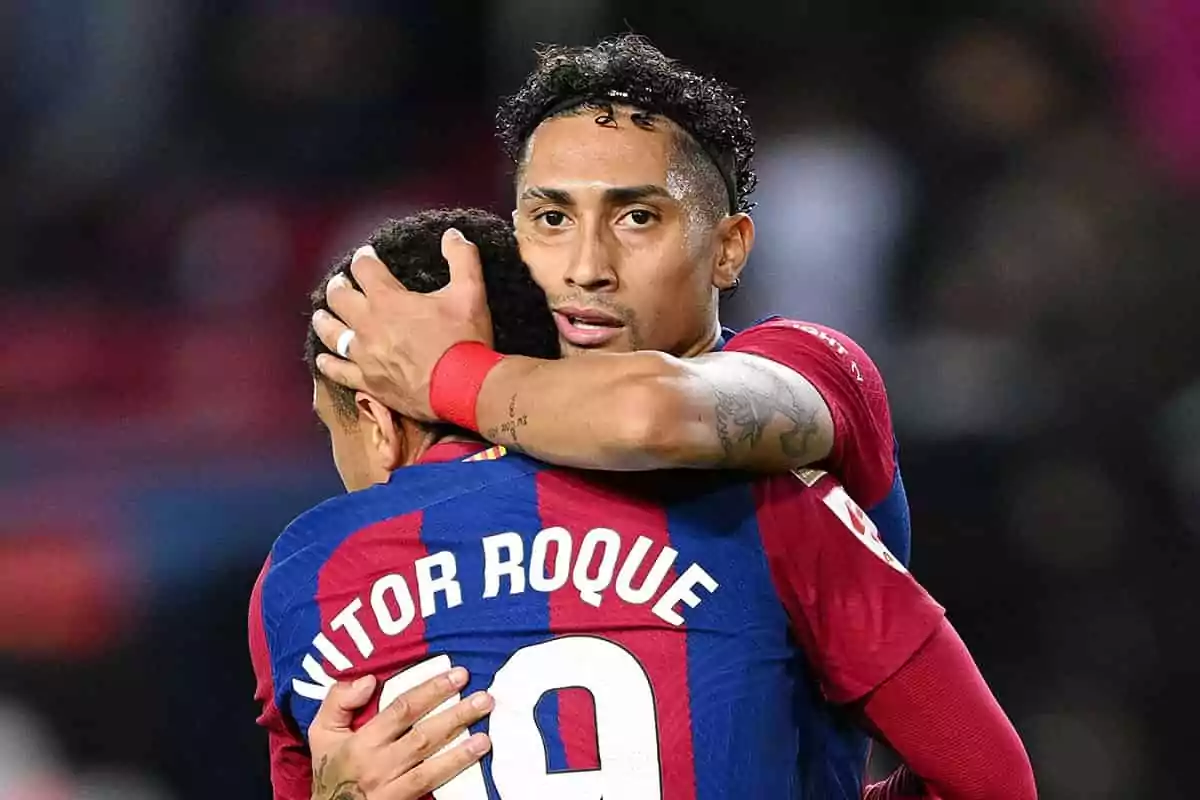 Dos jugadores de fútbol del FC Barcelona se abrazan en el campo, uno de ellos lleva el nombre Dos jugadores de fútbol del FC Barcelona se abrazan en el campo, uno de ellos lleva el nombre