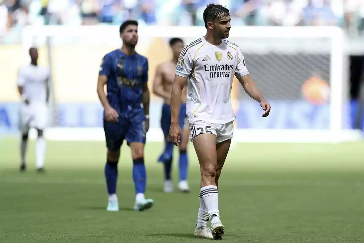 Futbolista del Real Madrid caminando en el campo durante un partido con jugadores rivales al fondo Futbolista del Real Madrid caminando en el campo durante un partido con jugadores rivales al fondo