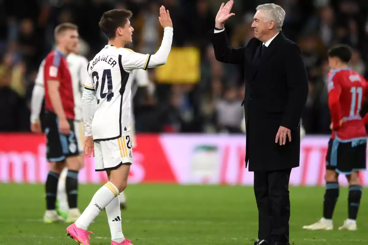 A soccer player and a coach shake hands on the field during a match.