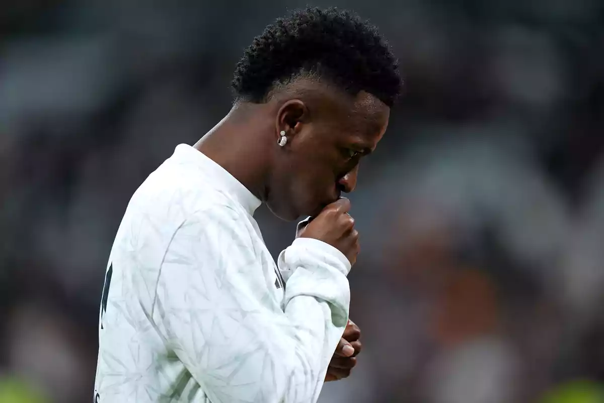 A soccer player kisses the crest on his jersey in a gesture of concentration and emotion before the match.