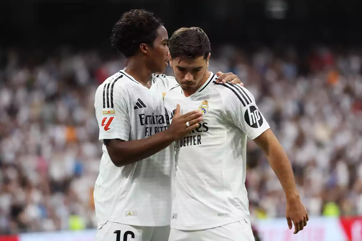 Two Real Madrid soccer players on the field, one of them appears to be consoling the other.