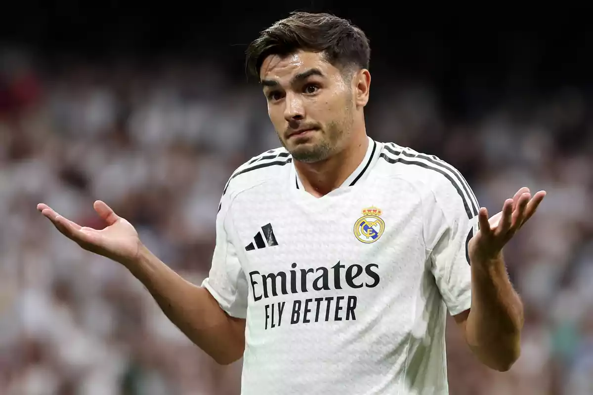 soccer player in white Real Madrid uniform raising his hands in a gesture of doubt during a match.