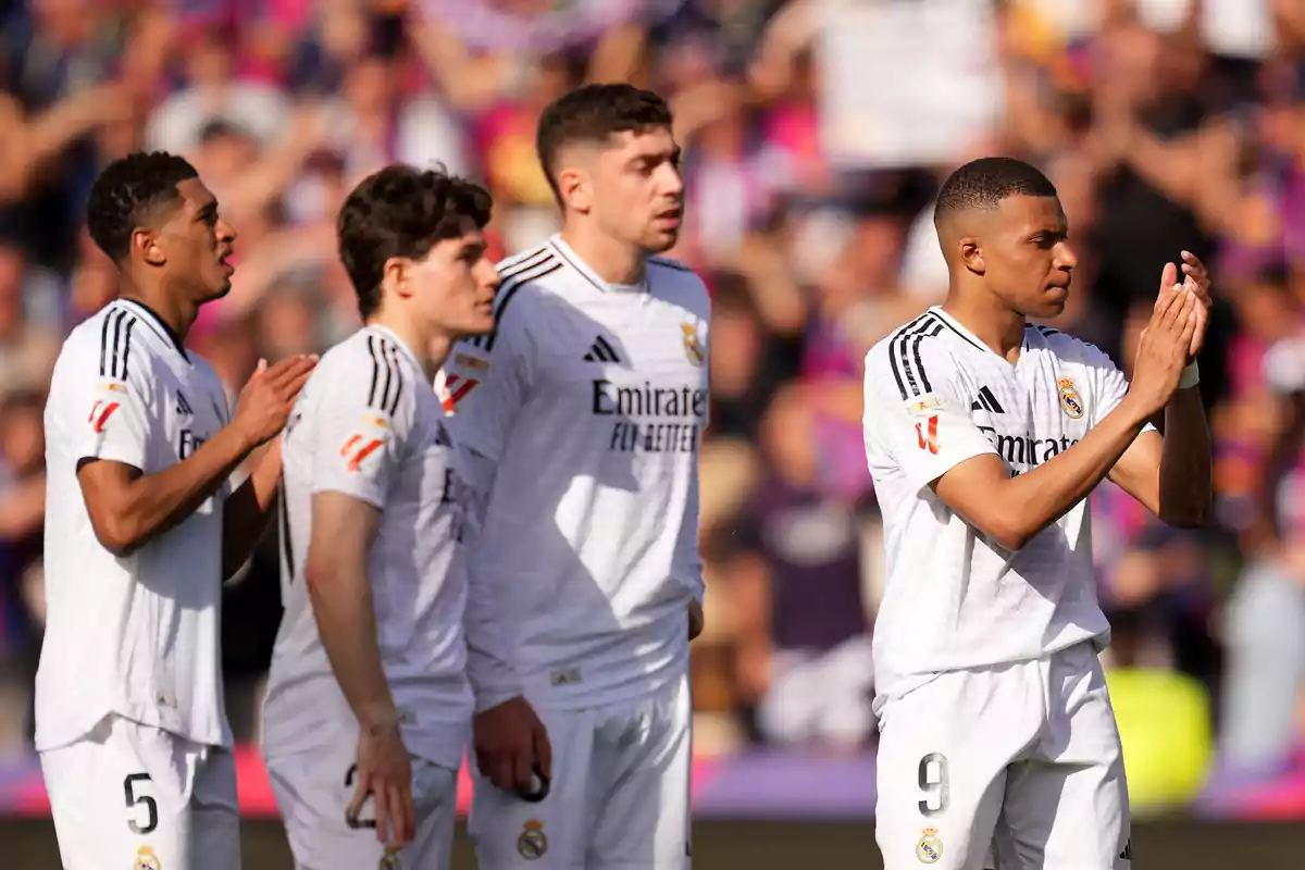 Jugadores de fútbol con uniforme blanco aplaudiendo en un estadio lleno de espectadores. Jugadores de fútbol con uniforme blanco aplaudiendo en un estadio lleno de espectadores.