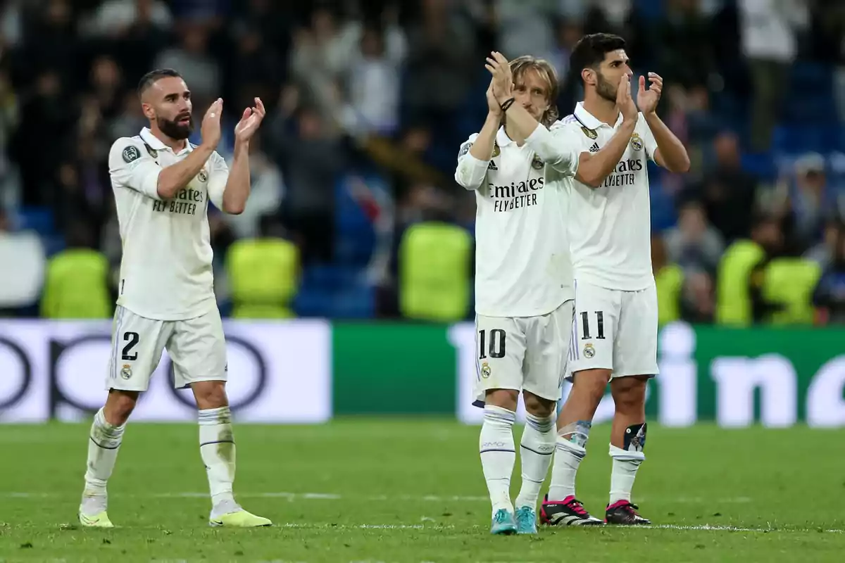 Three Real Madrid players applaud on the field after a soccer match