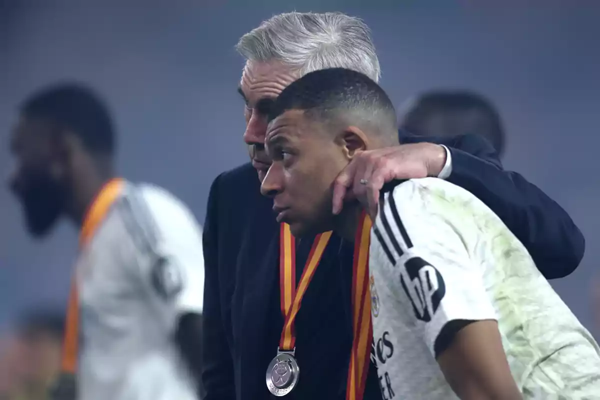 A coach hugs a player wearing a medal around his neck. A coach hugs a player wearing a medal around his neck.