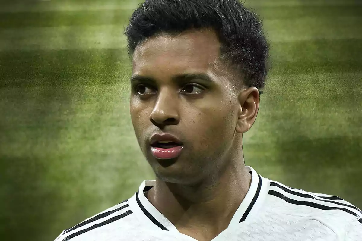 Jugador de fútbol con camiseta blanca y detalles negros en un campo de césped